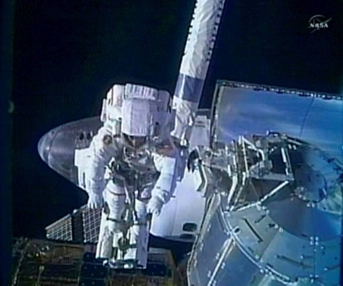 Este framegrab TV de la NASA muestra al astronauta Steve Bowen, del transbordador Discovery, en el extremo del brazo robótico durante la primera caminata espacial. AFP HO