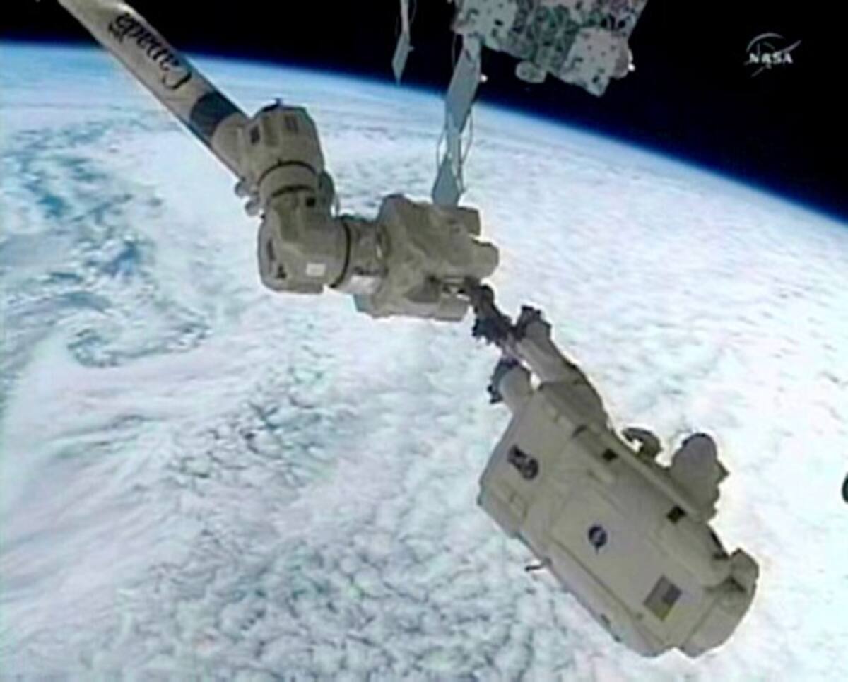 Este framegrab TV de la NASA muestra al astronauta Steve Bowen, del transbordador Discovery, en el extremo del brazo robótico durante la primera caminata espacial. AFP HO