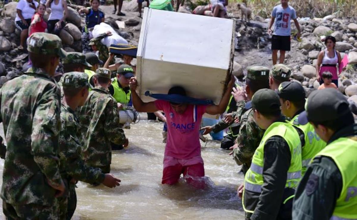 Los colombianos dejan Venezuela pasando sus pertenencias a través del río Táchira. AFP LUIS ACOSTA