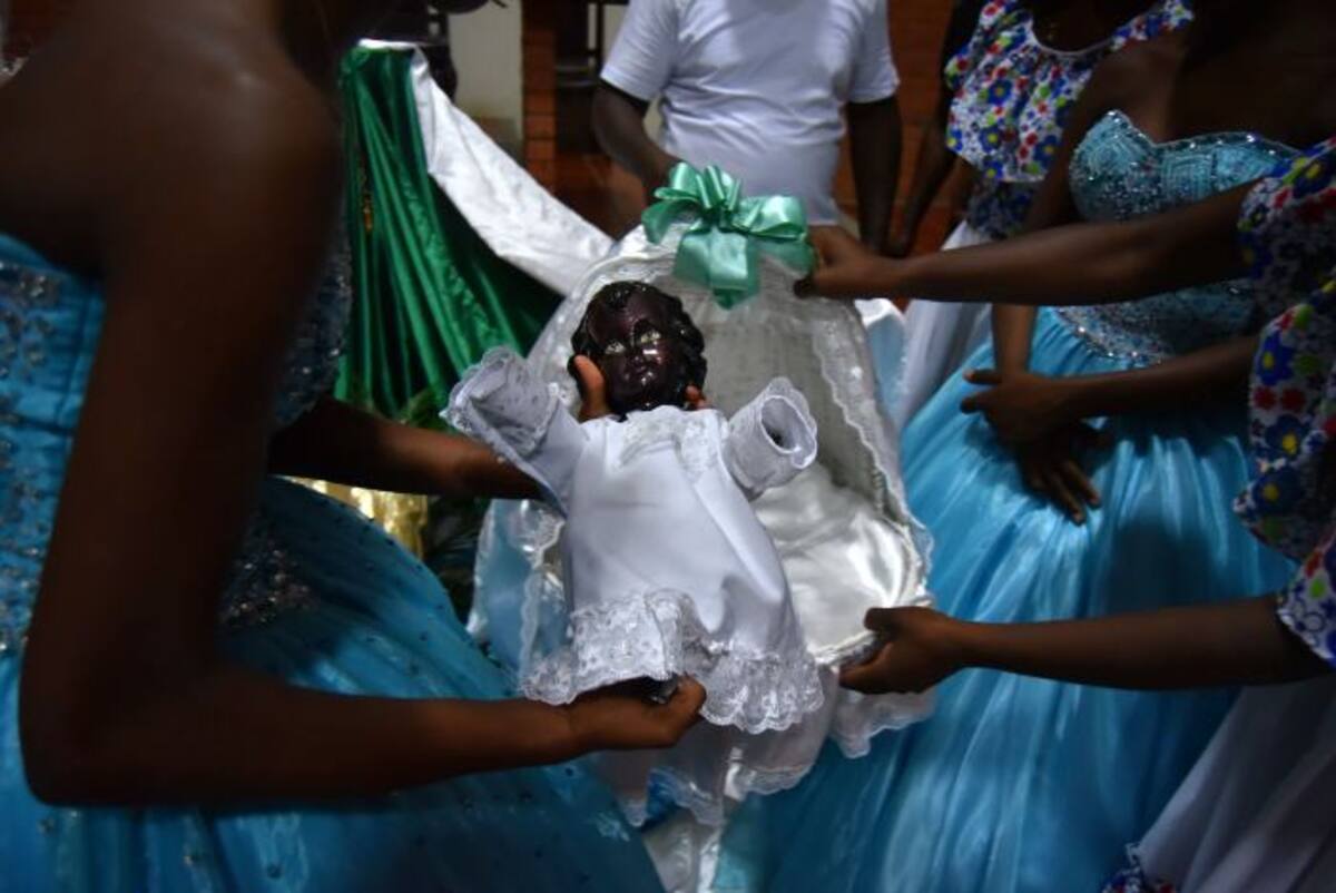 Jóvenes cargan la imagen del Niño Dios negro durante la celebración Adoración al Niño Dios este domingo. EFE