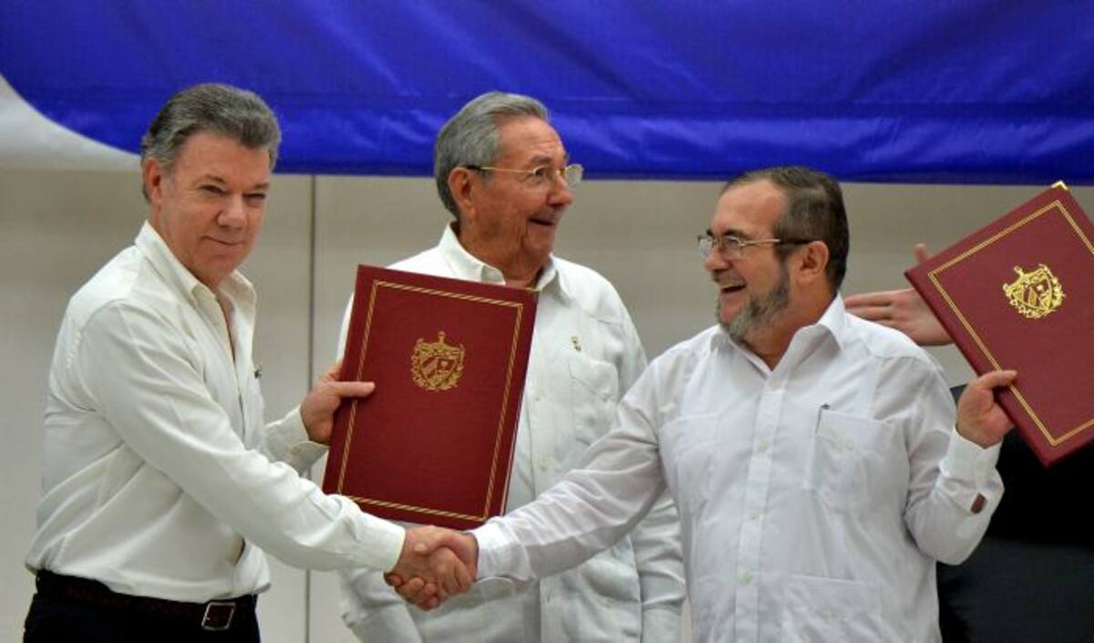 Momentos en que Juan Manuel Santos y alias "Timochenko" firman el acuerdo de paz. AFP ADALBERTO ROQUE