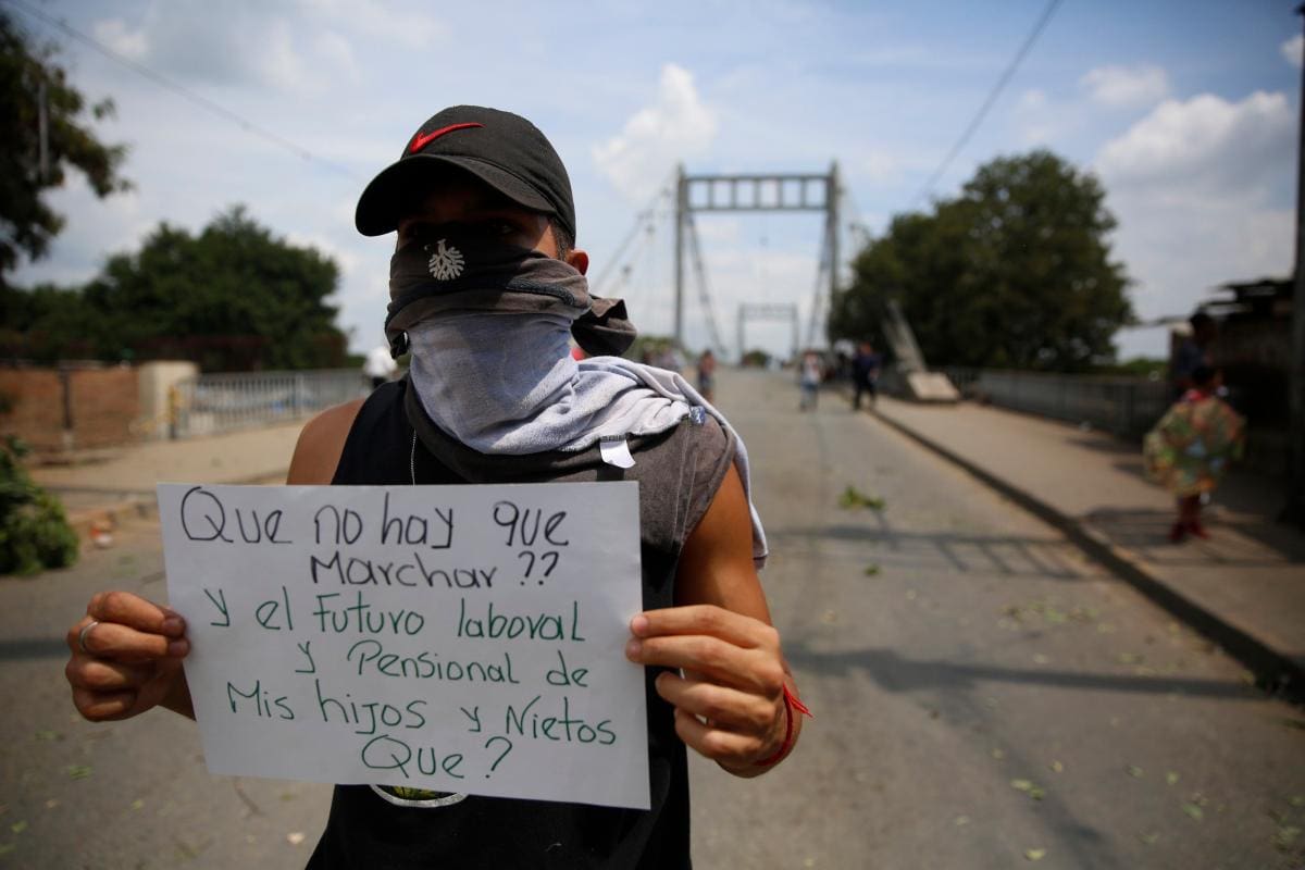 Un manifestante en Cali sostiene un cartel durante la tercera jornada de “paro nacional” contra el Gobierno del presidente Iván Duque para rechazar sus políticas económicas y sociales. EFE ERNESTO GUZMAN JR