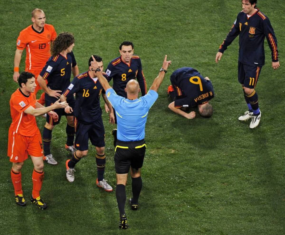 Referee Howard Webb of England (C) stops play to call a foul as Spain's midfielder Andrés Iniesta (2nd R) lies on the ground as Netherlands' midfielder Mark van Bommel (L) protests during the 2010 World Cup football final between the Netherlands and Spain on July 11, 2010 at Soccer City stadium in Soweto, suburban Johannesburg. NO PUSH TO MOBILE / MOBILE USE SOLELY WITHIN EDITORIAL ARTICLE AFP PHOTO / GIANLUIGI GUERCIA