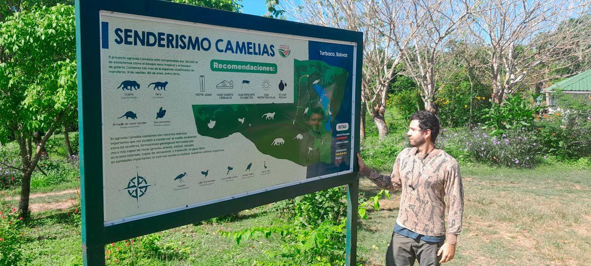 Rafael Camacho, en la valla con el mapa de senderismo de Agrícola Camelias. // HFA _ EU.