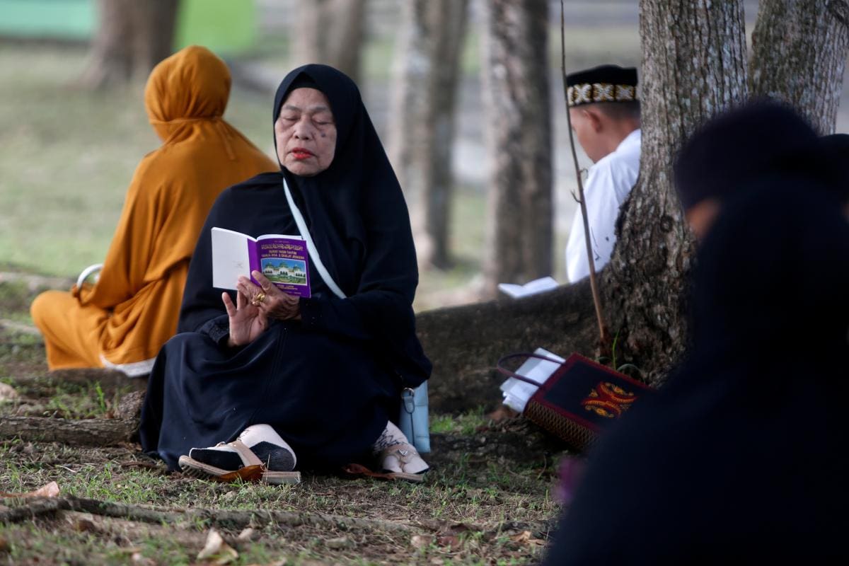 El pueblo de Aceh reza y lee el Sagrado Corán en una fosa común para las víctimas del tsunami. // Foto: EFE.