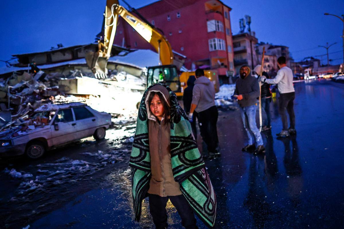 Familiares de desaparecidos esperan frente a un edificio derrumbado mientras el equipo de emergencia los busca después de un poderoso terremoto en el distrito de Elbistan en Kahramanmaras, sureste de Turquía.
