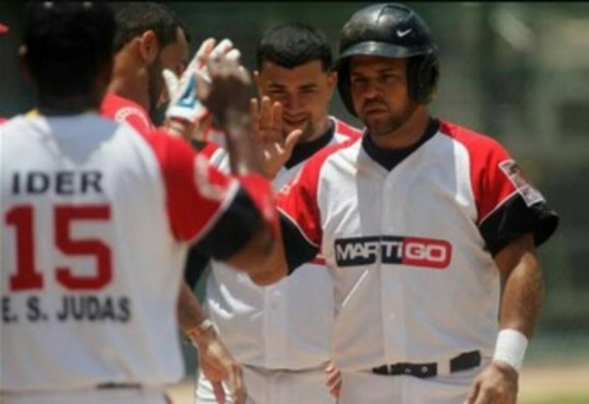 Sergio Baena, de Martigo, es felicitado por sus compañeros, luego de anotar una de las carreras del triunfo de su equipo 6-4 ante Sacsa. Archivo.