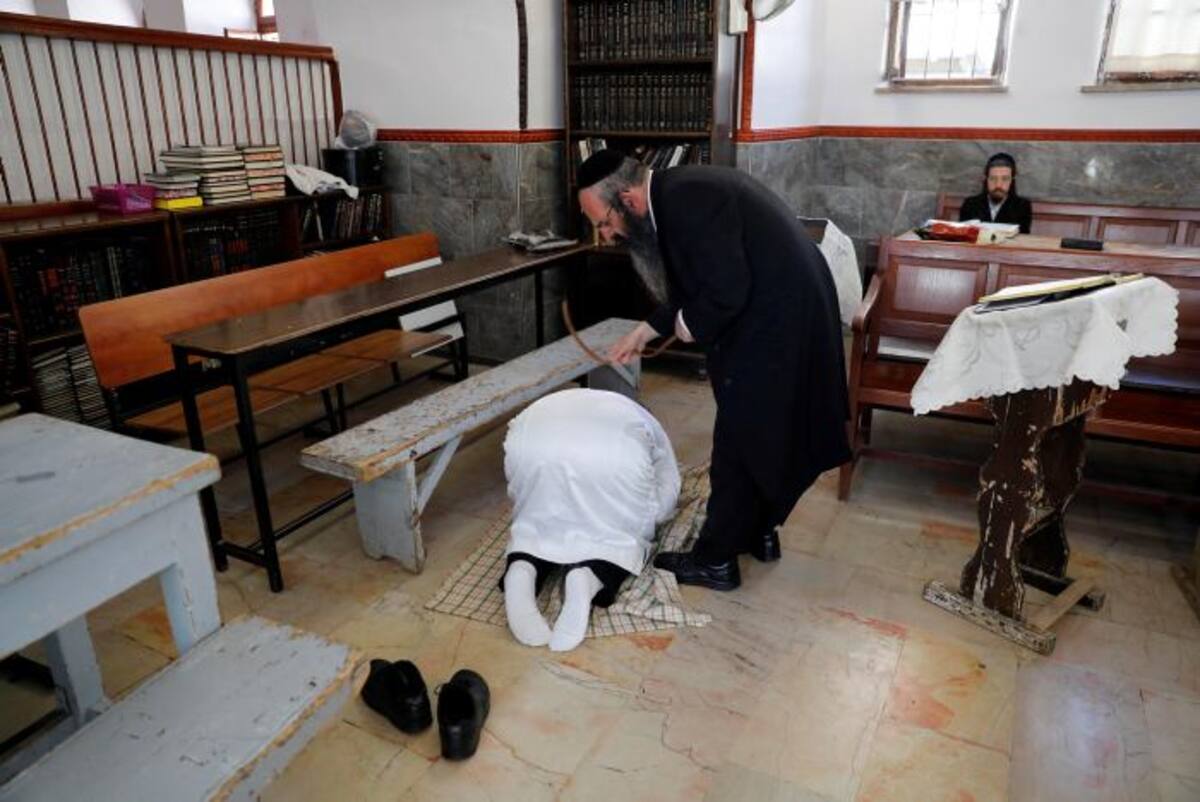 Un judío ultra ortodoxo fustiga a otro con una correa de piel como castigo simbólico por sus pecados en el barrio de Mea Shearim. Los judíos celebran hoy durante el anochecer el Yom Kipur, día de la expiación, perdón y el arrepentimiento, que dura 25 horas. EFE ABIR SULTAN