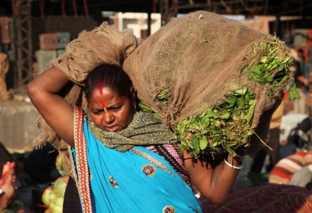 Una mujer de India carga un saco de vegetales en el Día Internacional de la Mujer. CHANNI ANAND-AP.