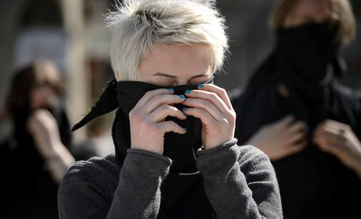Mujer cubre su rostro con una pañoleta negra durante un performance en honor al feminismo en Bucarest, Rumania. ANDREEA ALEXANDRU-AP.