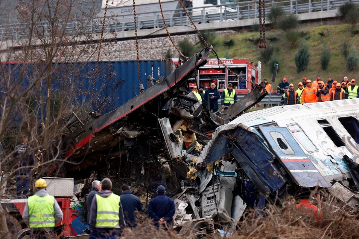 Vehículos grúa intentan retirar piezas de un vagón de tren dañado.