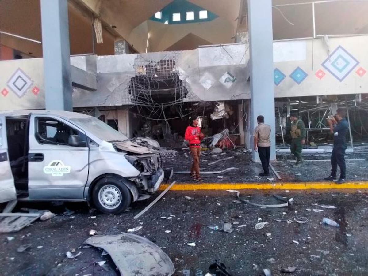 Los transeúntes y un soldado se paran cerca de una parte dañada del aeropuerto de la ciudad de Adén, en el sur de Yemen. AP Majid Saleh