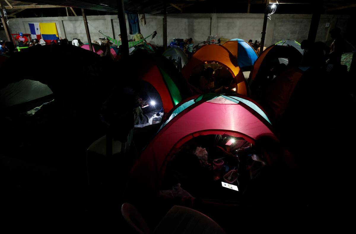Migrantes usan sus celulares en un albergue en Capurganá (Colombia). //EFE