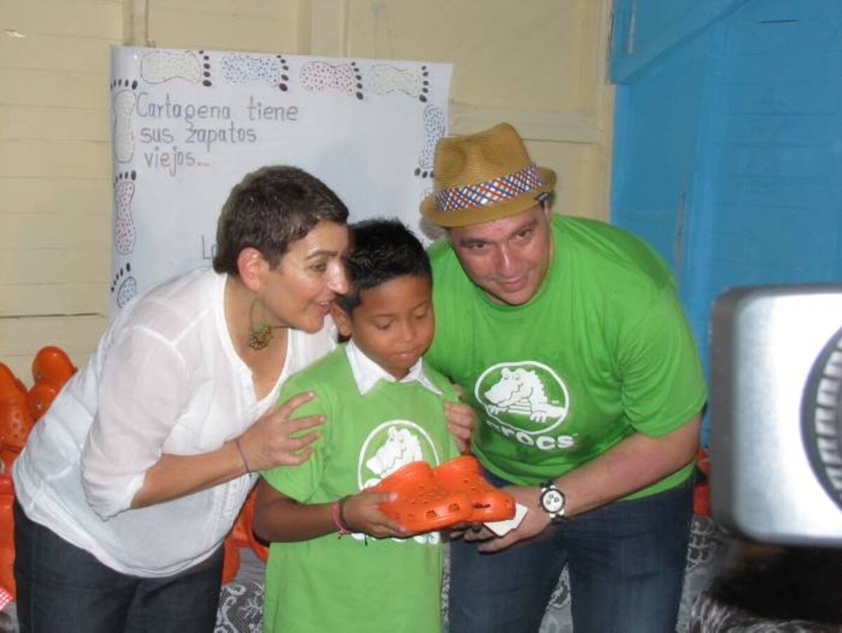 Patricia Sierra, directora de la Fundación Pies Descalzos, y David Atias, representante de la empresa donante, entregan zapatos a uno de los niños de la Loma del Peyé. Yirian Babilonia