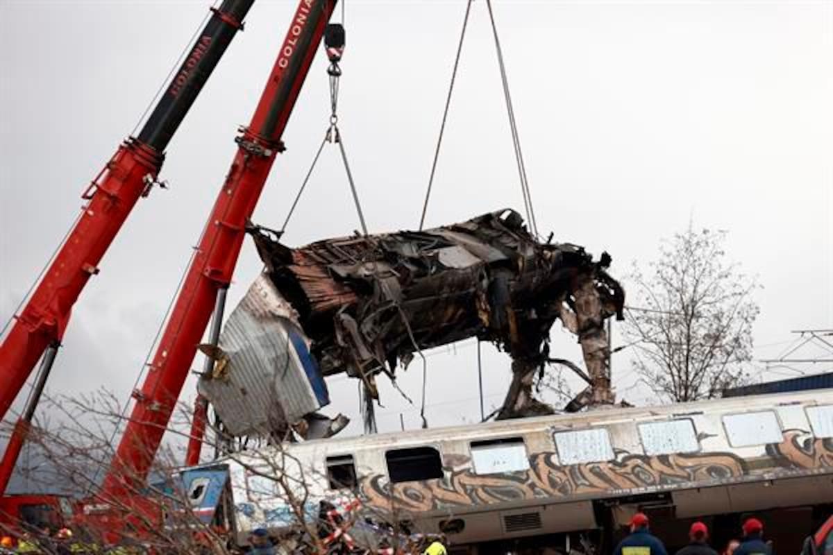 Vehículos grúa intentan retirar piezas de un vagón de tren dañado.