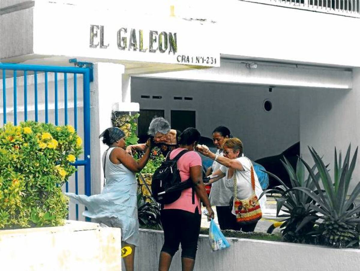 En esta imagen varias personas se emplean a fondo para ayudar a una señora a evadir el agua.