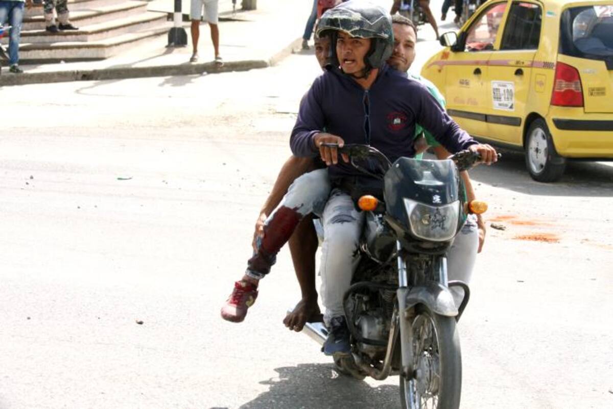 Un hombre que resultó herido a bala en una de sus piernas es llevado a un centro asistencial en una motocicleta.