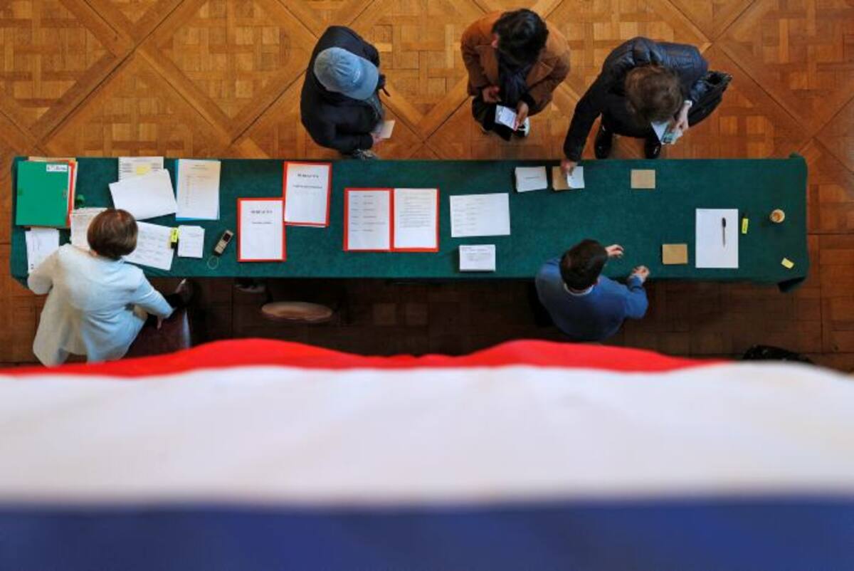La bandera francesa se cuelga de una balaustrada mientras los votantes emiten sus votos en la elección presidencial. AP