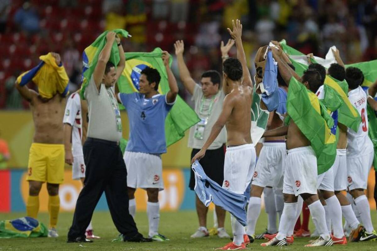 Jugadores tahitianos elevan banderas de Brasil, al finalizar su partido contra Uruguay. AFP JUAN BARRETO