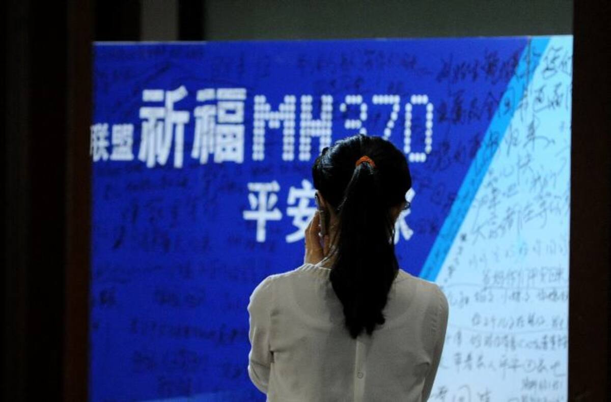 Una familiar de uno de los pasajeros observa una pancarta con mensajes para los desaparecidos. AFP WANG ZHAO