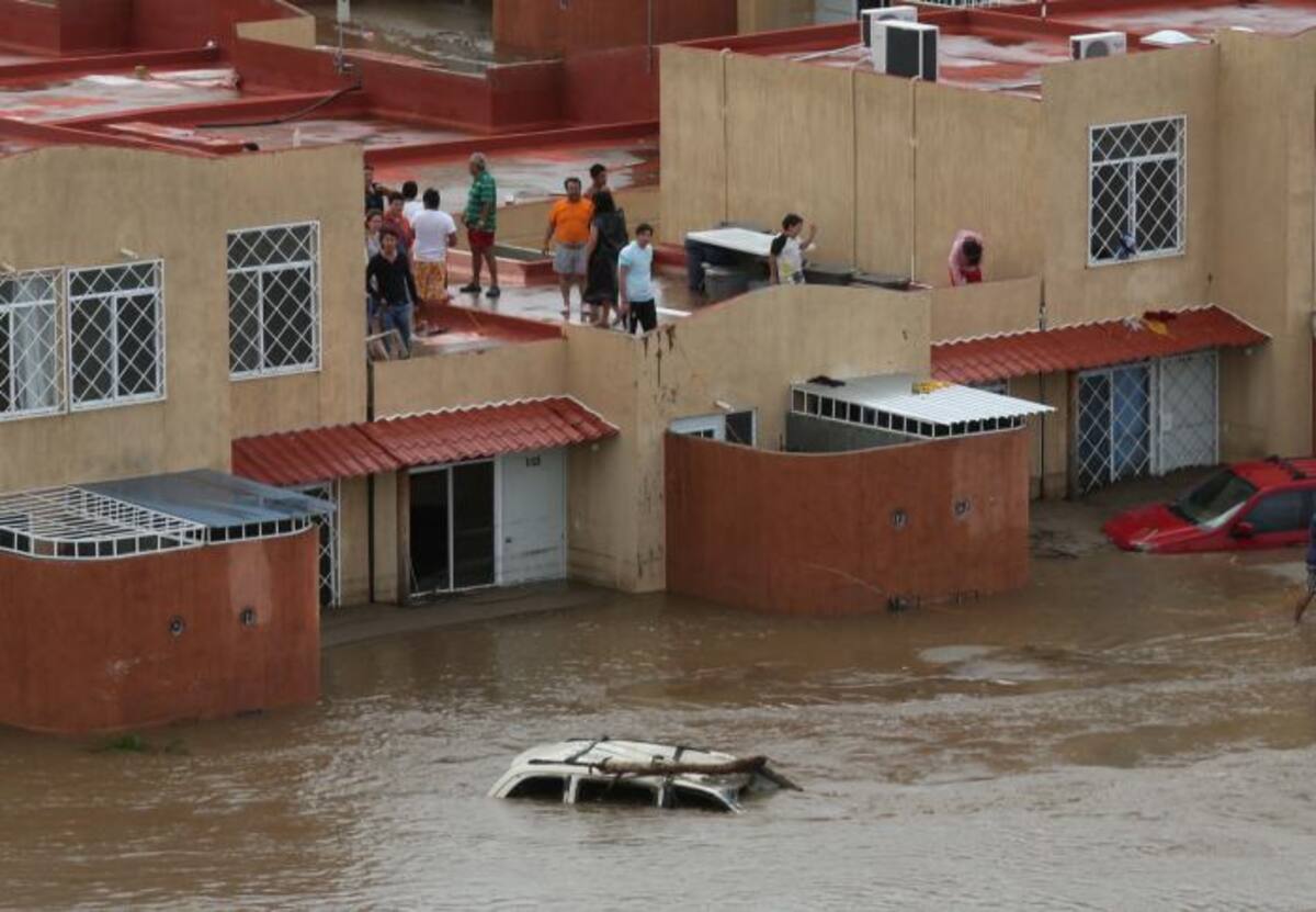 Estas personas tuvieron que subirse al techo de su casa para no poner en riesgo su vida. AFP