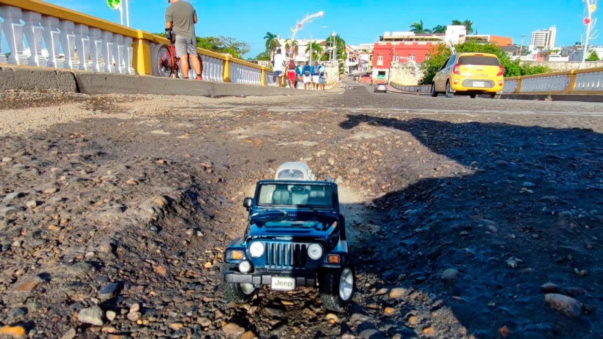 Dos carros en miniatura, un Jeep Wrangler y un Volkswagen clásico alemán, padeciendo en su intento por transitar sobre el puente Román, hacen parte de la ingeniosa protesta. //Cortesía