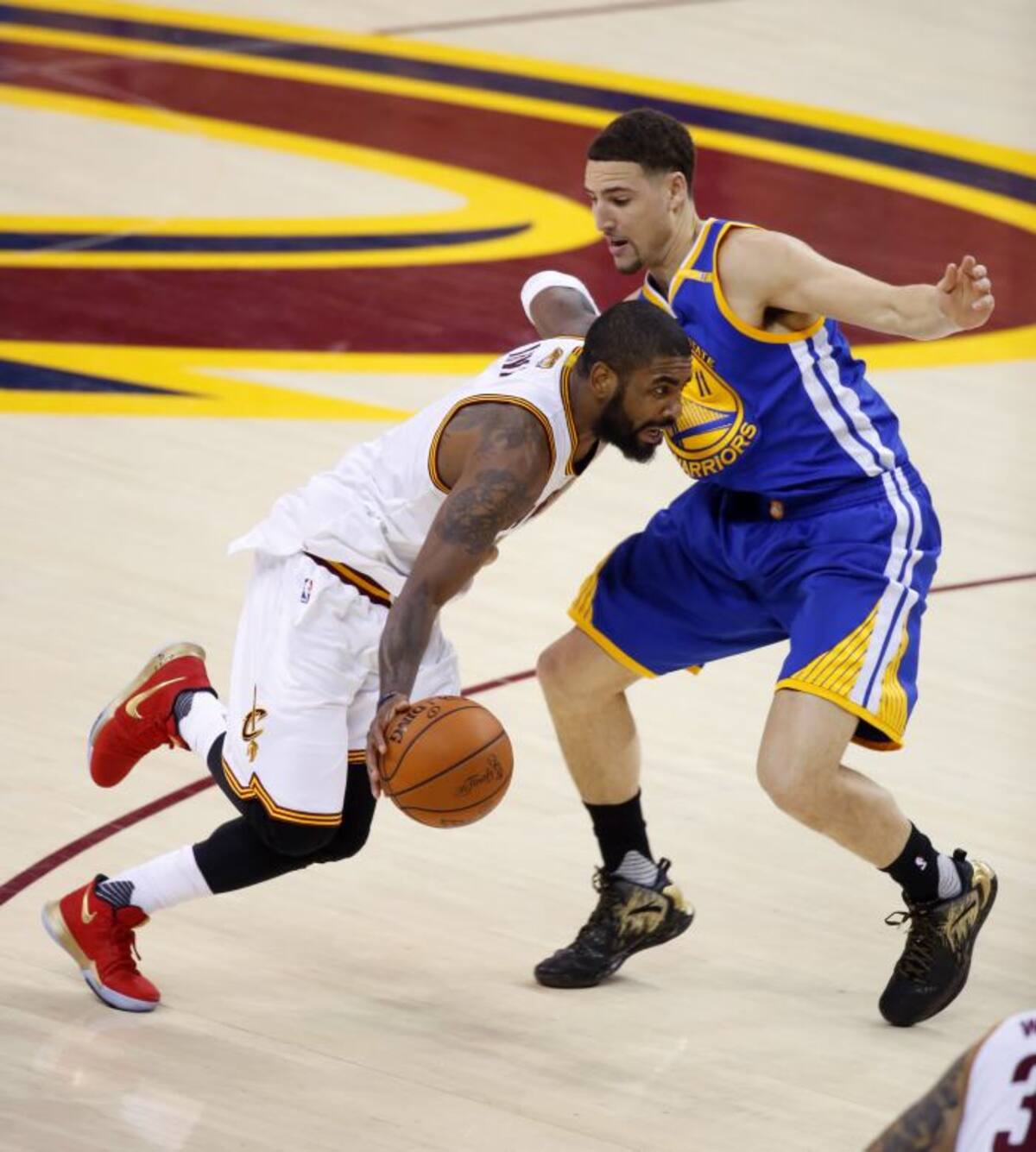 Kyle Irving, de Cleveland, intenta penetrar ante la marca de Klay Thompson, de Golden State, durante el cuarto juego de la NBA. .AP