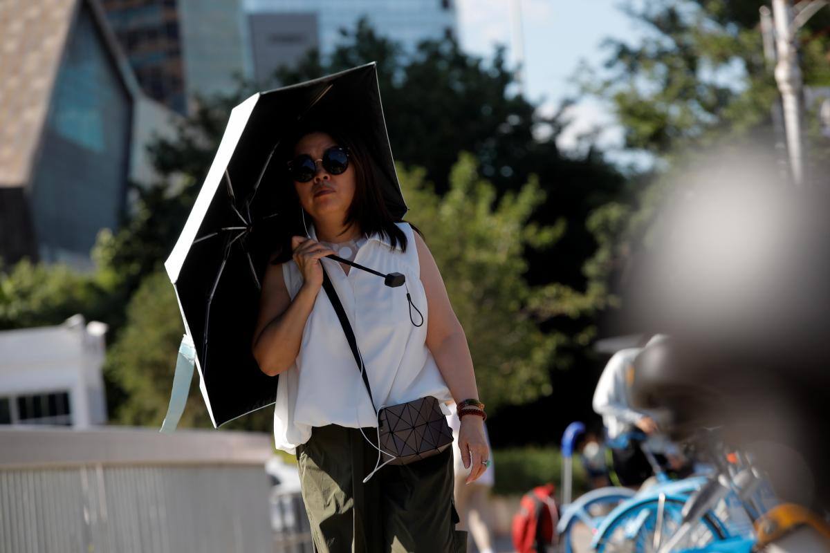 Una mujer que se protege del sol con un paragüas en Beijing (China). //EFE