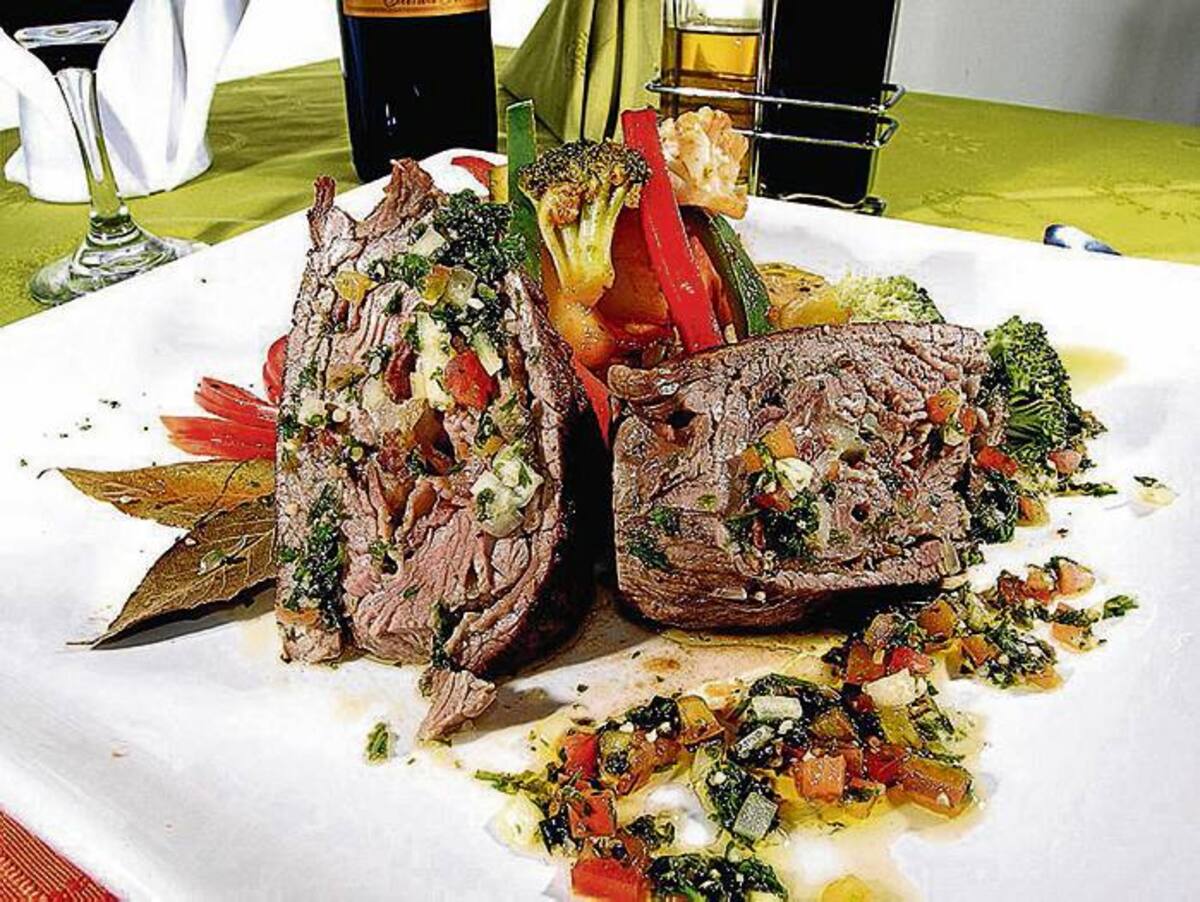 Lomo mediterráneo. Lomo relleno de tocineta, tomates secos y basílico, bañado con una marinada de aceite de oliva. Se acompaña con vegetales y papas al vapor.