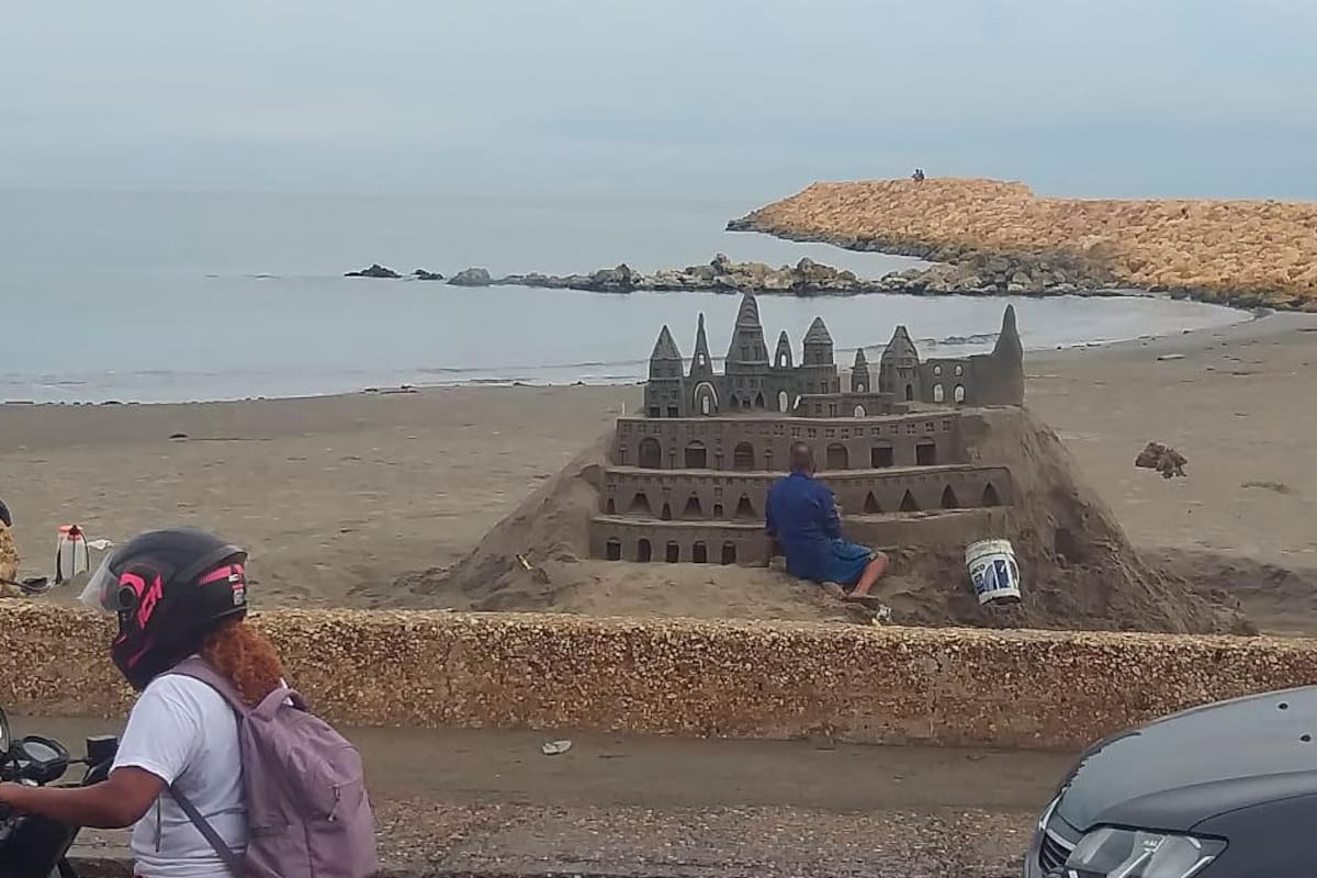 Padre e hijo arman castillo de arena en Marbella, mientras la lluvia lo permita