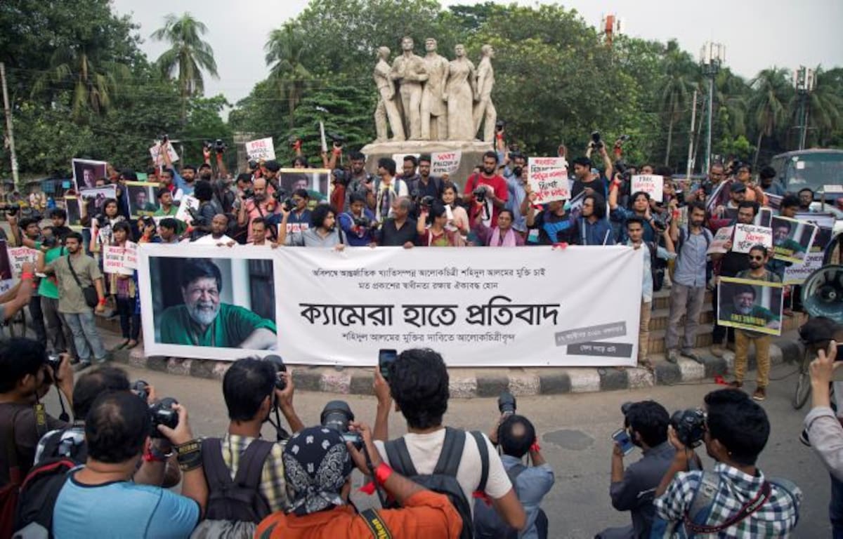 Un grupo de fotógrafos forma una cadena humana mientras sostienen carteles y pancartas para protestar por la detención de Shahudil Alam, compañero de profesión, en Dacca, Bangladesh. EFE MONIRUL ALAM