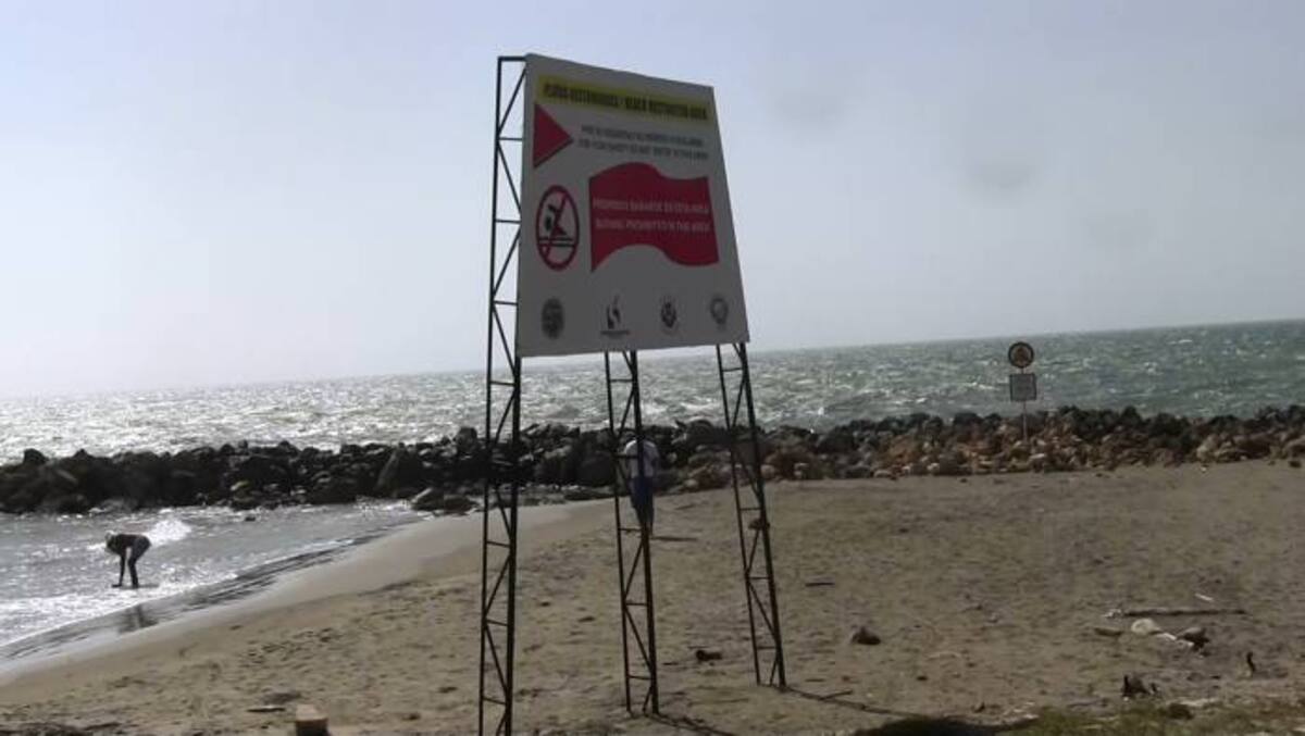 A pesar de la valla de restricción, estos dos bañistas se alistan para bañarse en el mar de La Tenaza. ELUNIVERSAL.COM.CO