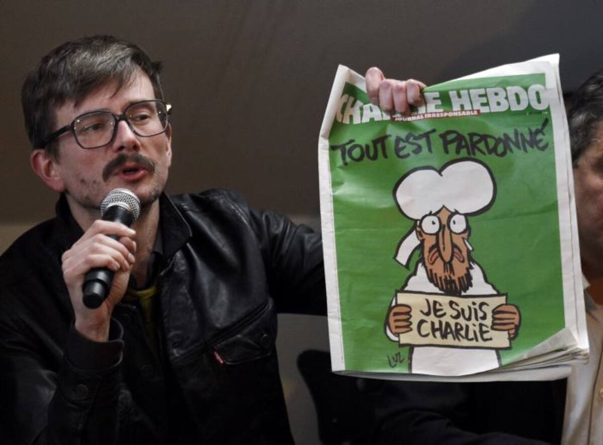 El caricaturista Renald Luzier con la portada de mañana del semanario satírico. AFP MARTIN BUREAU