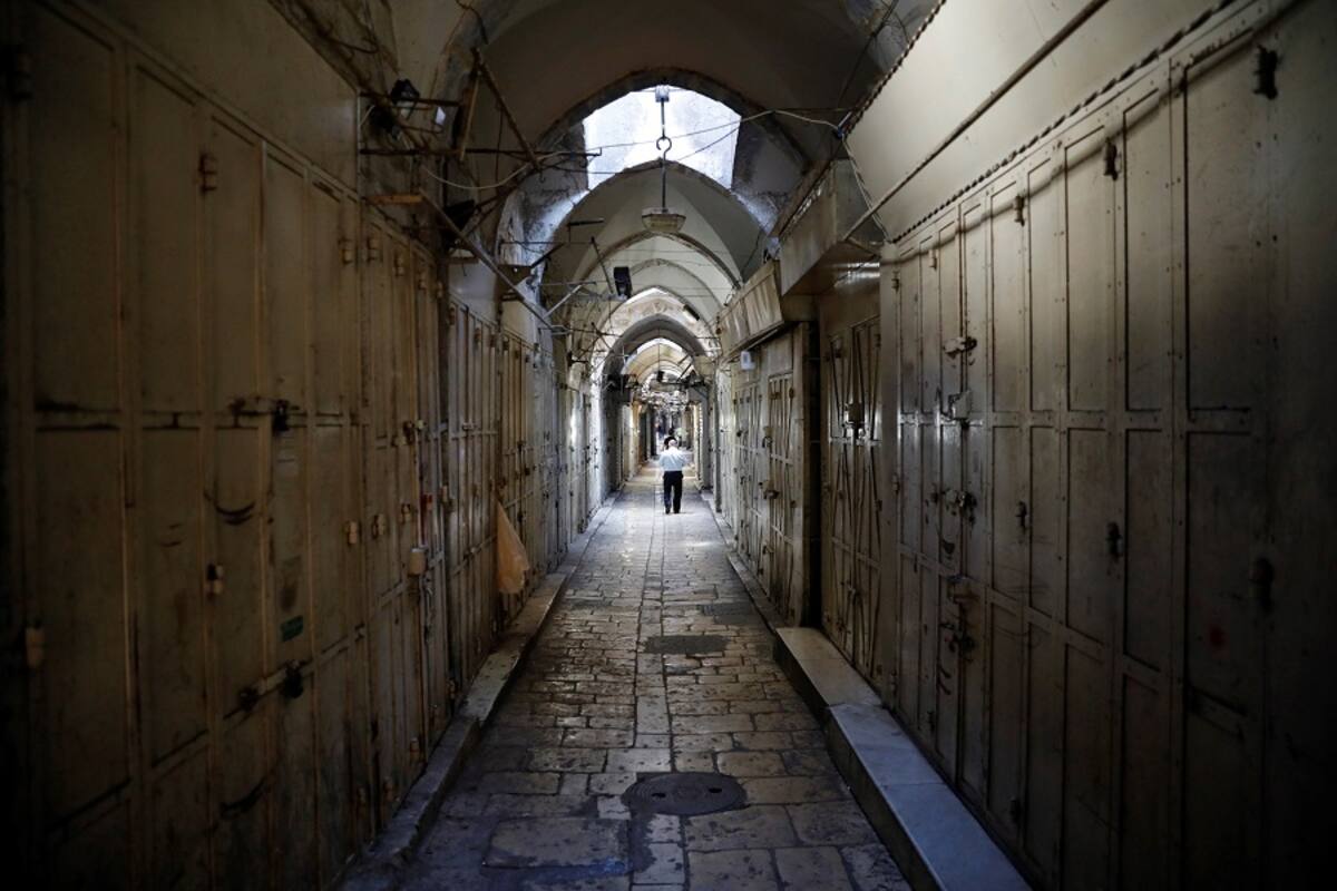 Un palestino camina entre las tiendas, que permanecen cerradas, del mercado de la Ciudad Vieja de Jerusalén. EFE