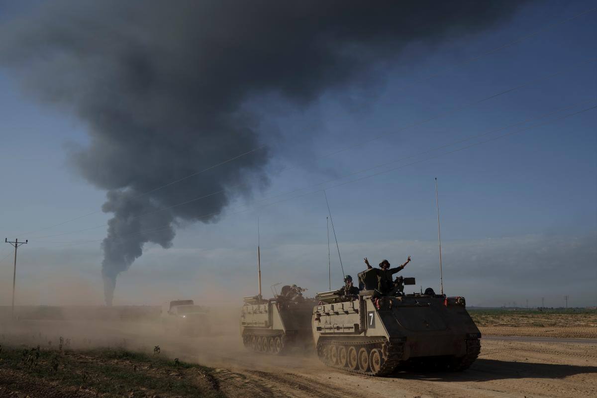 Soldados israelíes se mueven en vehículos blindados de transporte de personal (APC) cerca de la frontera entre Israel y Gaza mientras el humo se eleva hacia el cielo en la Franja de Gaza. //AP.