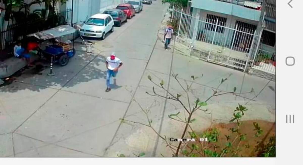 El presunto sicario, de gorra y suéter blanco, fue captado por cámaras de video del barrio cuando huía del lugar.