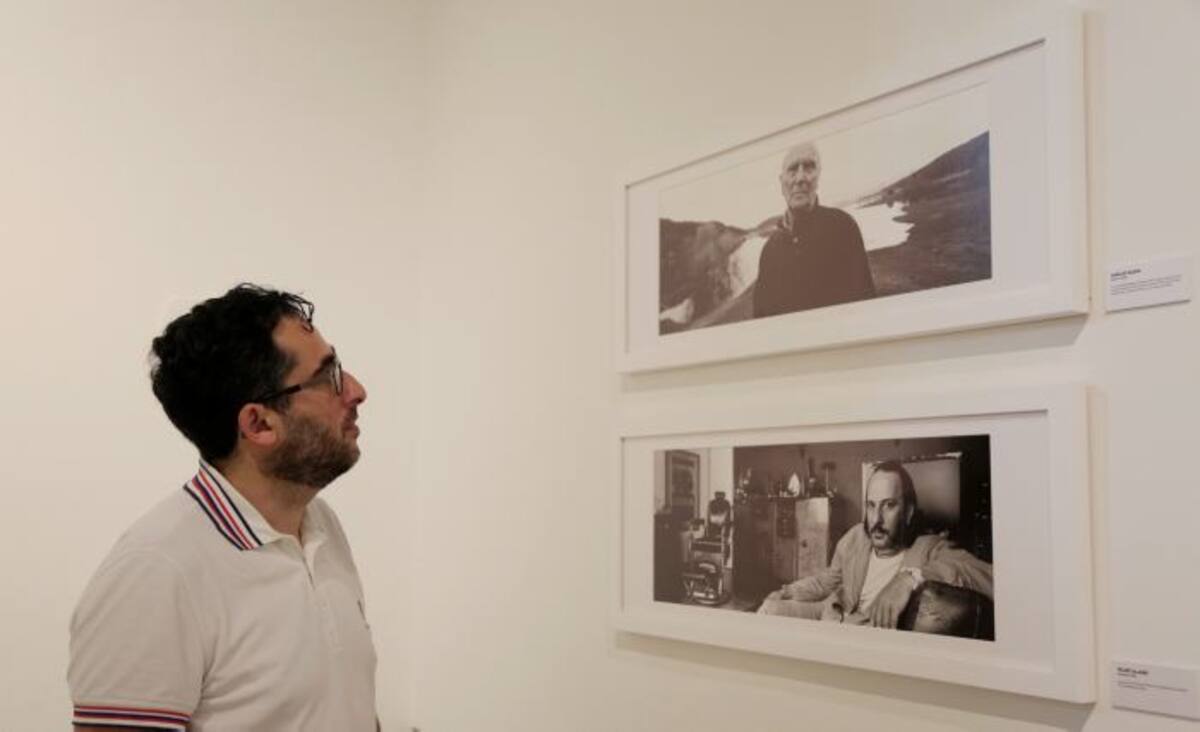 El fotógrafo español Óscar Fernández Orengo mientras observa dos de las fotografías que forman parte de su exposición "Seguimos rodando". EFE.