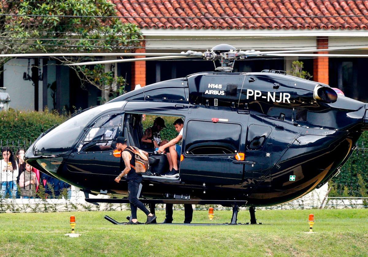 El delantero Neymar llega este domingo en su helicóptero junto con sus compañeros de la selección brasileña Dani Alves (izq) y Thiago Silva (der) al centro de entrenamiento de la Granja Comary, en Teresópolis (Brasil). EFE/ Antonio Lacerda