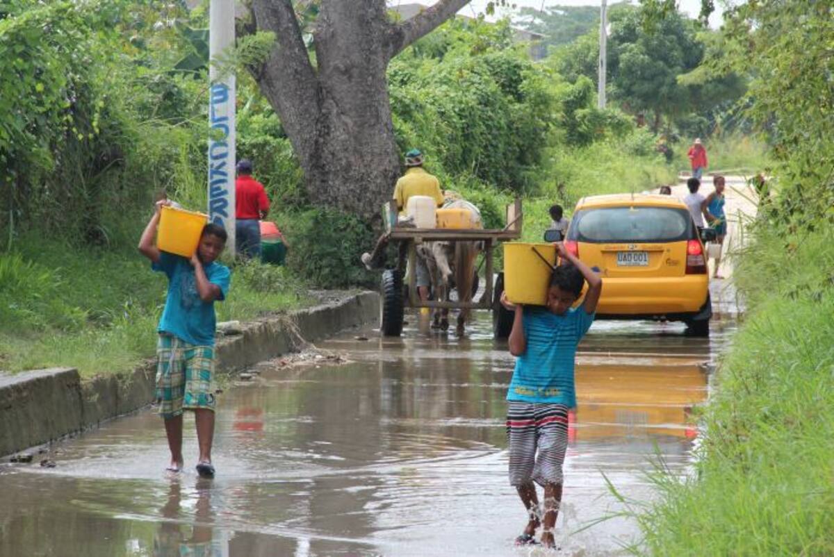 Entre Villagrande de Indias y San José de los Campanos, algunas personas recogen agua que corre por una calle. Gabriel J. García G.