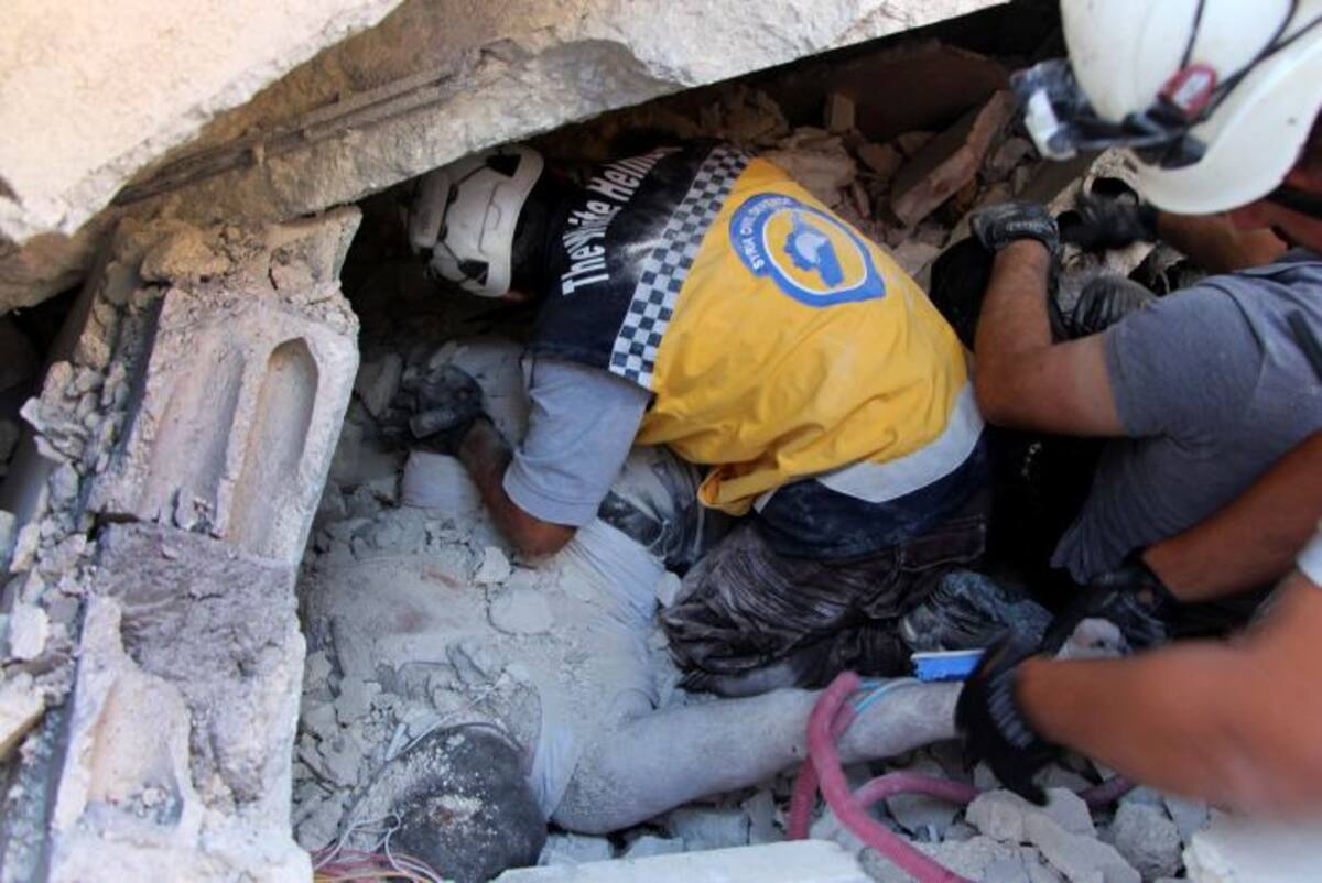 Miembros de la Defensa Civil en Siria rescatan cuerpos de los escombros. AP