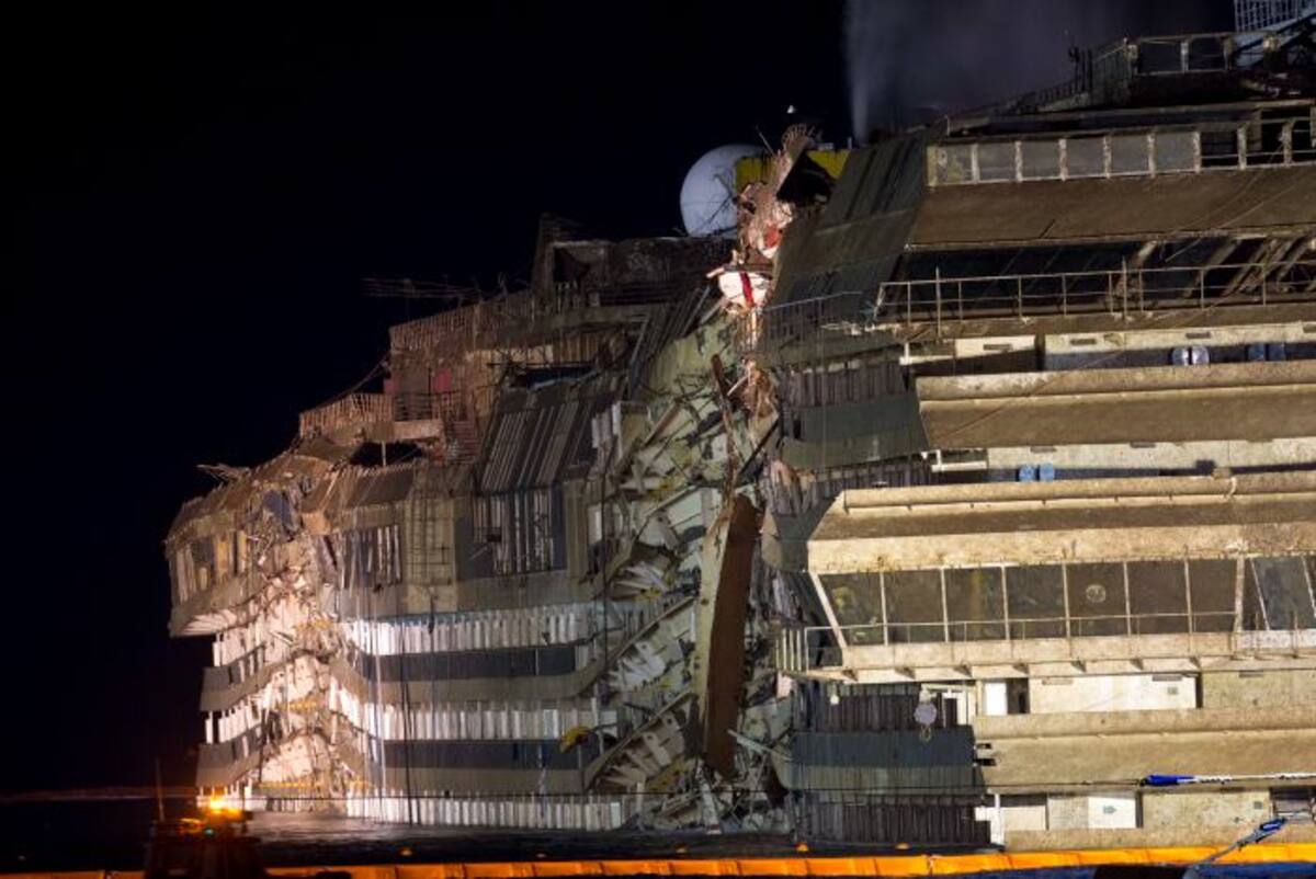 Por la noche, la imponente silueta iluminada del palace flotante, con el flanco roñoso después de pasar 20 meses debajo del agua, destacaba delante del puerto, donde se congregaban cientos de personas emocionadas. AP Andrew Medichini