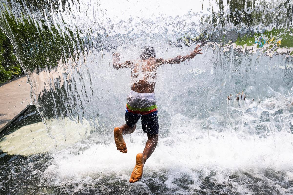 Un niño refrescándose en una fuente con cascada en Yards Park, Washington (EE. UU.) //EFE.