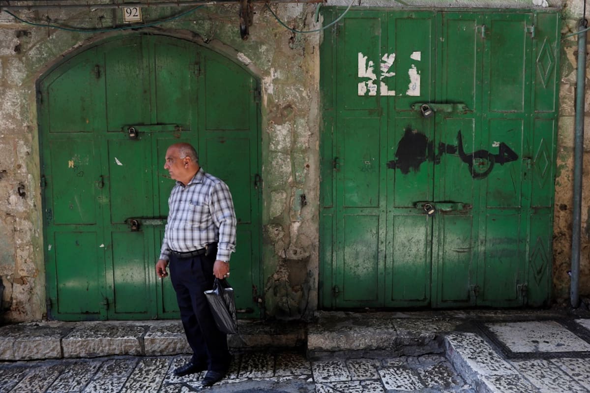 Un palestino camina entre las tiendas, que permanecen cerradas, del mercado de la Ciudad Vieja de Jerusalén. EFE