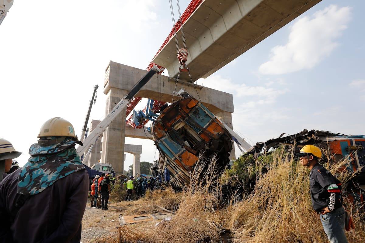 Rescatistas trabajan en los restos de un tren de pasajeros tras el desplome de una grúa de construcción en Tailandia. //EFE/EPA/NARONG SANGNAK.