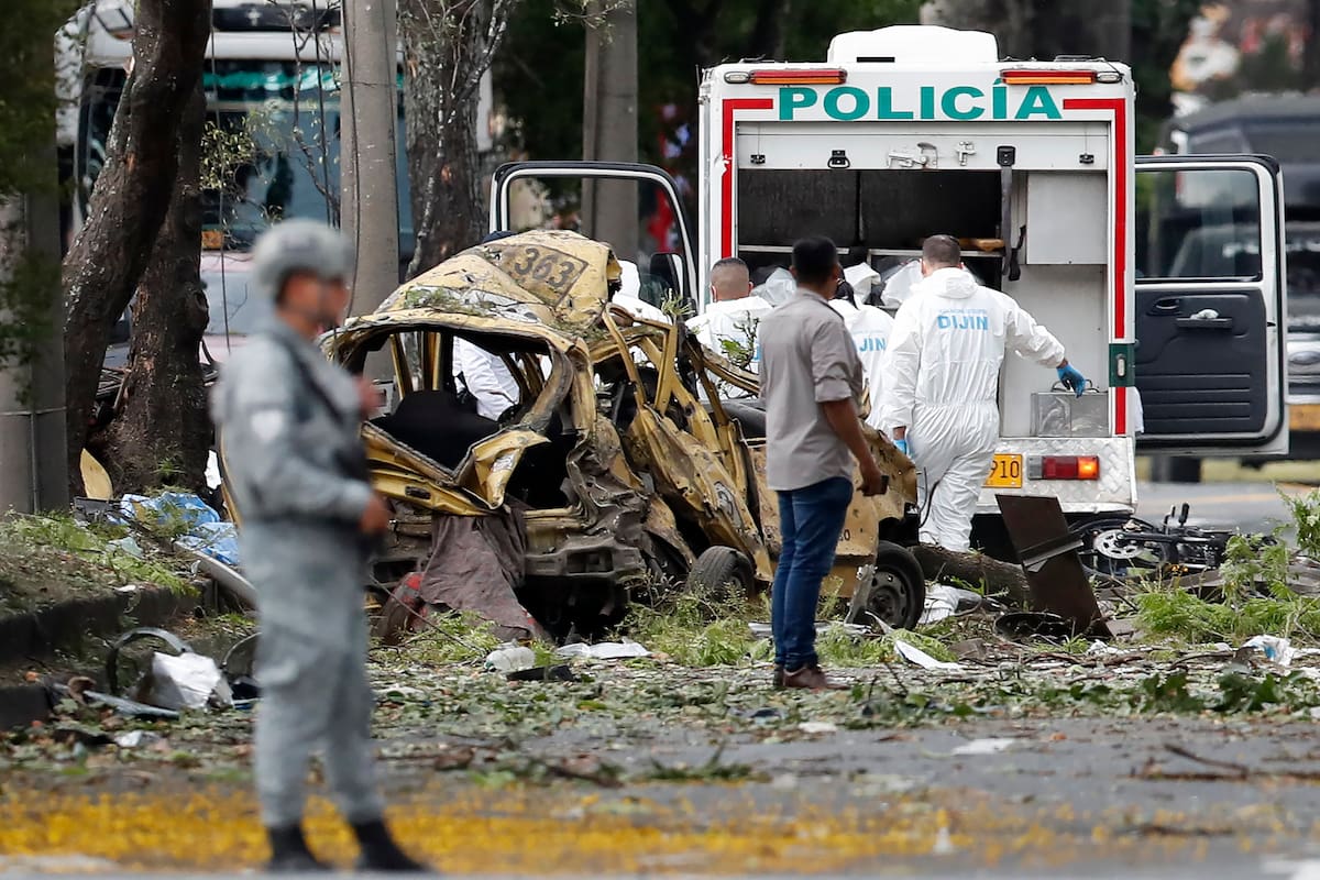 Integrantes de la Dirección de Investigación Criminal e Interpol (DIJIN) inspeccionan un vehículo afectado tras una explosión en inmediaciones de la Escuela Militar de Aviación Marco Fidel Suárez este jueves, en Cali (Colombia). Al menos cinco personas murieron y 36 resultaron heridas por un atentado perpetrado con un camión bomba. EFE/