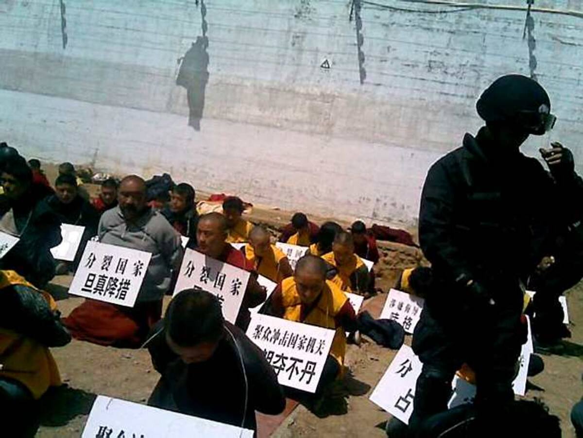 Los monjes con la cabeza baja y la pancarta al cuello. AFP FreeTibet