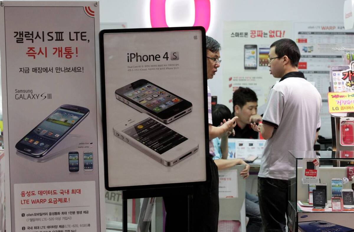 Banners de publicidad de Samsung Electronics Galaxy S III, a la izquierda, y del iPhone 4S de Apple se muestran en una tienda de telefonía móvil. AP Ahn Young-joon
