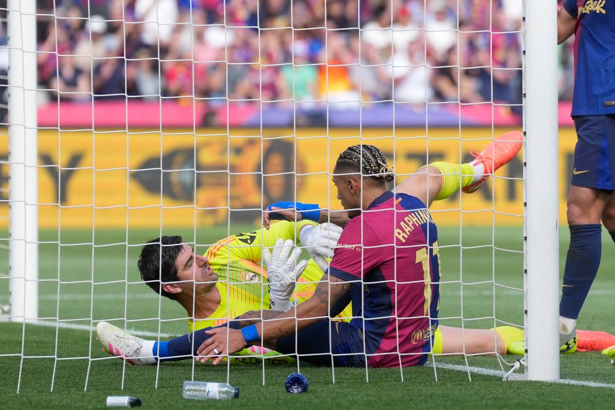 El delantero del Barcelona Raphinha y el portero del Real Madrid Thibaut Courtois durante el partido. //EFE