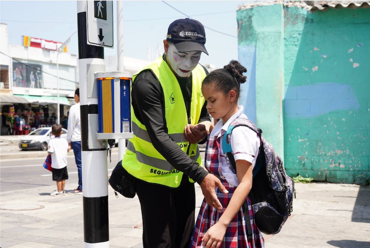 Un mimo ayuda a una niña en condición de discapacidad visual cómo utilizar la botonera para activar el pare en el semáforo.//Cortesía Alcaldia de Barranquilla.