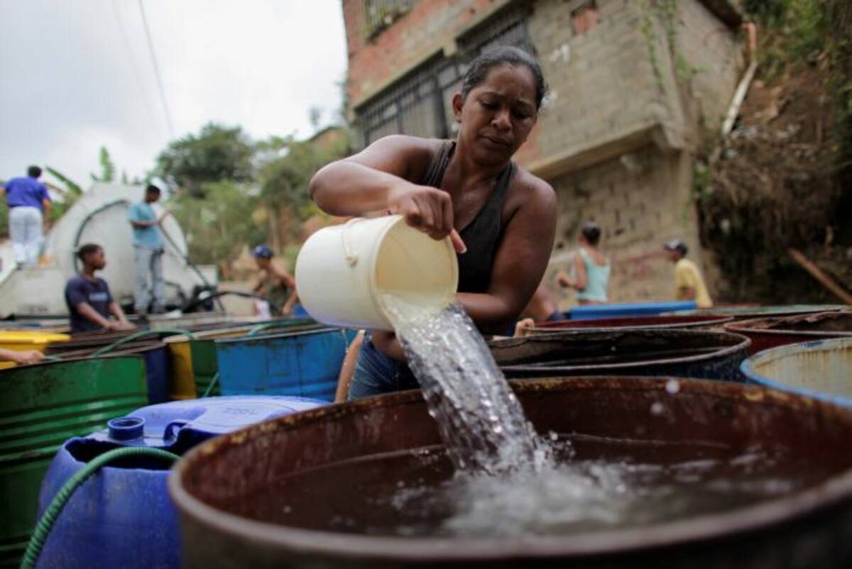 Una mujer llena barriles con agua fresca de un camión de distribución de agua en el barrio Filas de Mariches en Caracas. Archivo / AP Ariana Cubillos